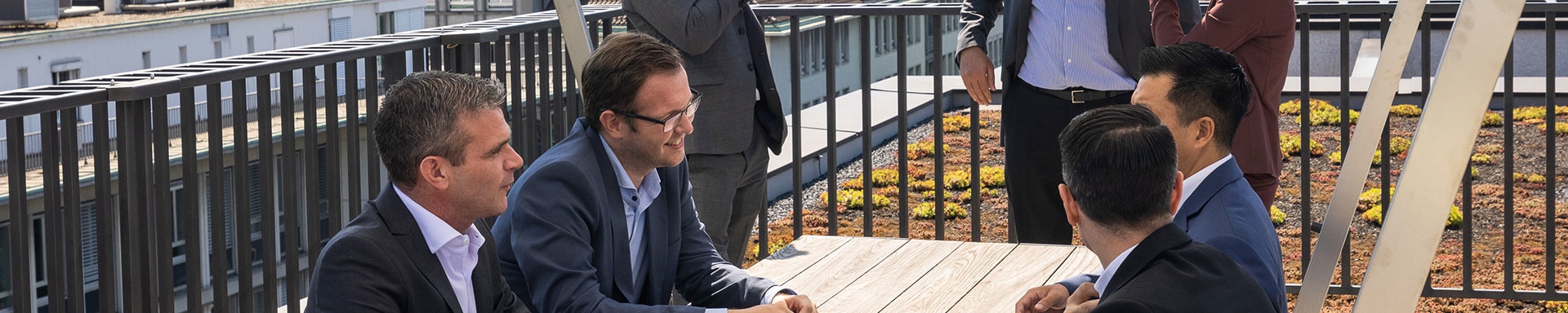 Members of the Transaction Banking team stand on the balcony at Vontobel's head office and talk to each other.