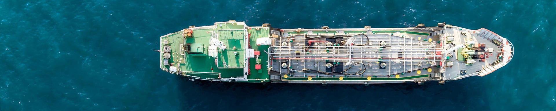 Ein Frachtschiff fährt auf dem offenen Meer und symbolisiert das Outsourcing von Trading Desks im Transaction Banking.