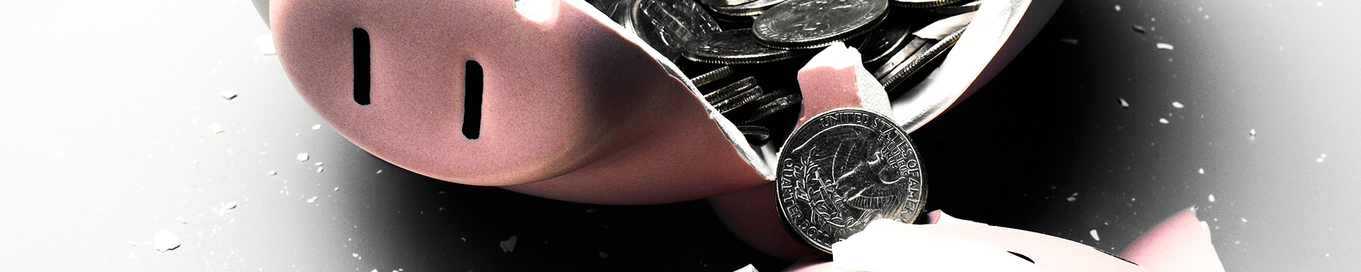 A broken piggy bank with coins spilling out, symbolizing accessed savings