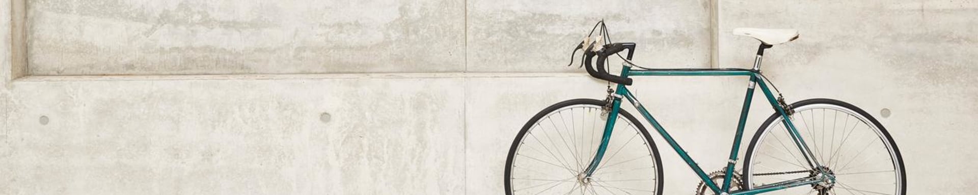 A green racing bike leaning against a concrete wall
