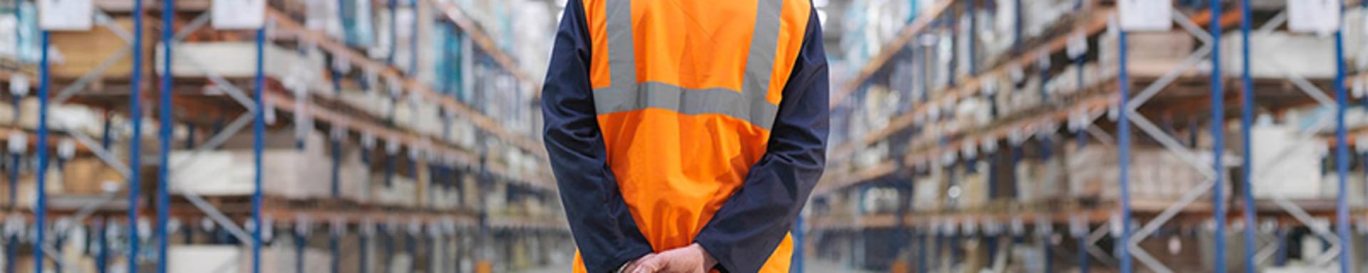 Man with orange vest standing in the warehouse