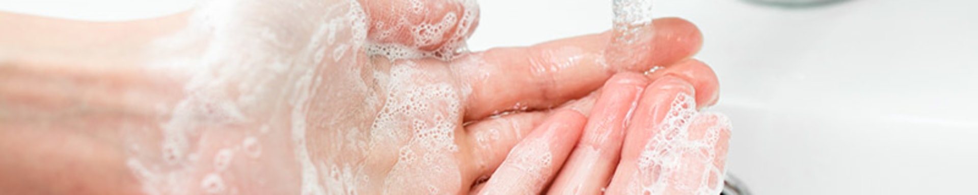 Eine Person wäscht sich die Hände mit einer Seife, die Corona visrus symbolisiert.