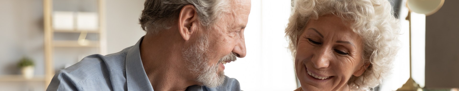 Elderly couple happily signing a contract together.