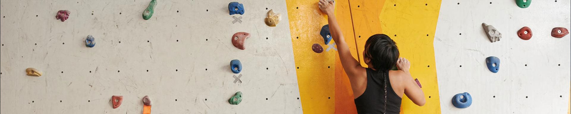 Eine Frau klettert eine Kletterwand hoch.