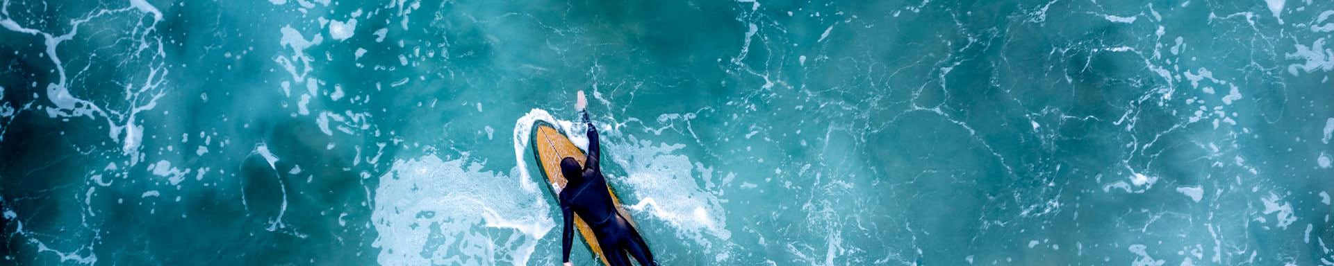 A surfer paddles through the turquoise water.