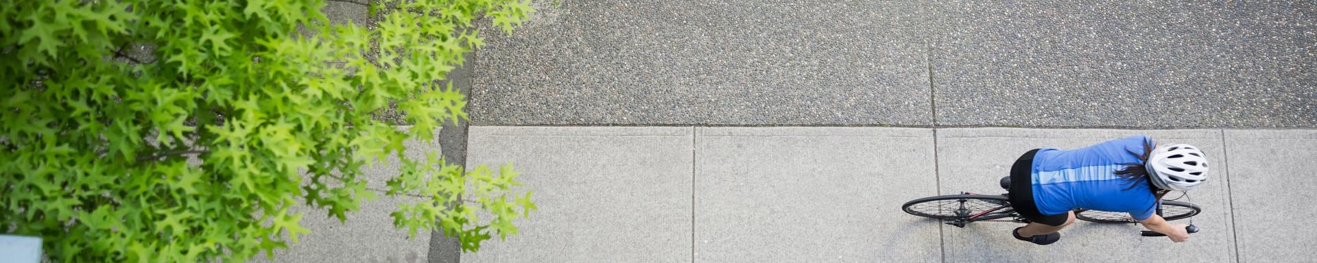 Bird's eye view from a balcony, down onto a woman riding a bicycle.