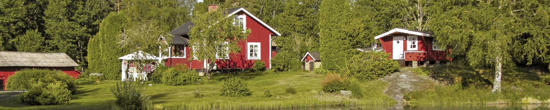 photo of three red wooden houses by a lake