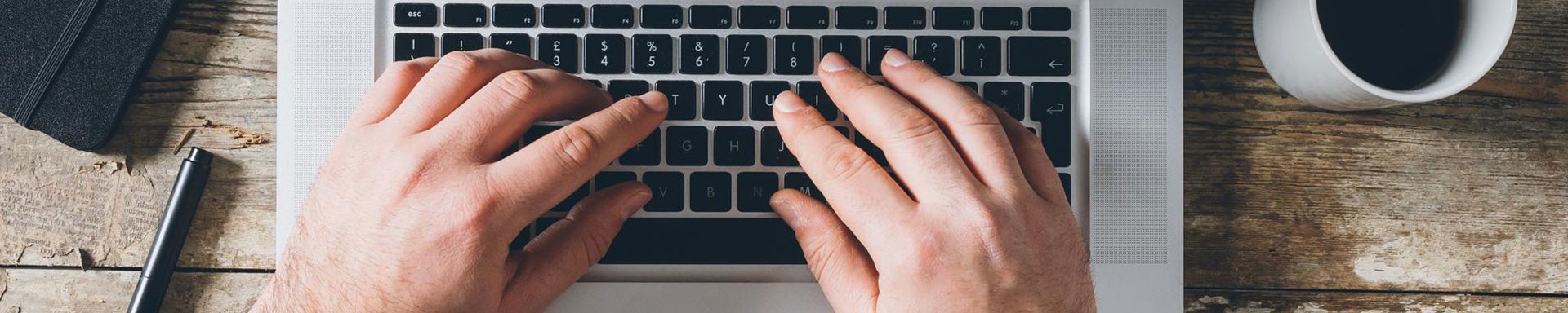 Ein Mann, der auf der Tastatur seines Laptops tippt und das das Kontaktformular für den Datenschutz ausfüllt.