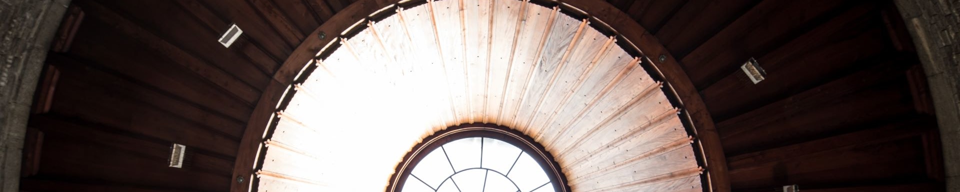 Architektonische Nahaufnahme eines kreisförmigen Oberlichts in einer hölzernen Kuppeldecke mit geometrischem Muster