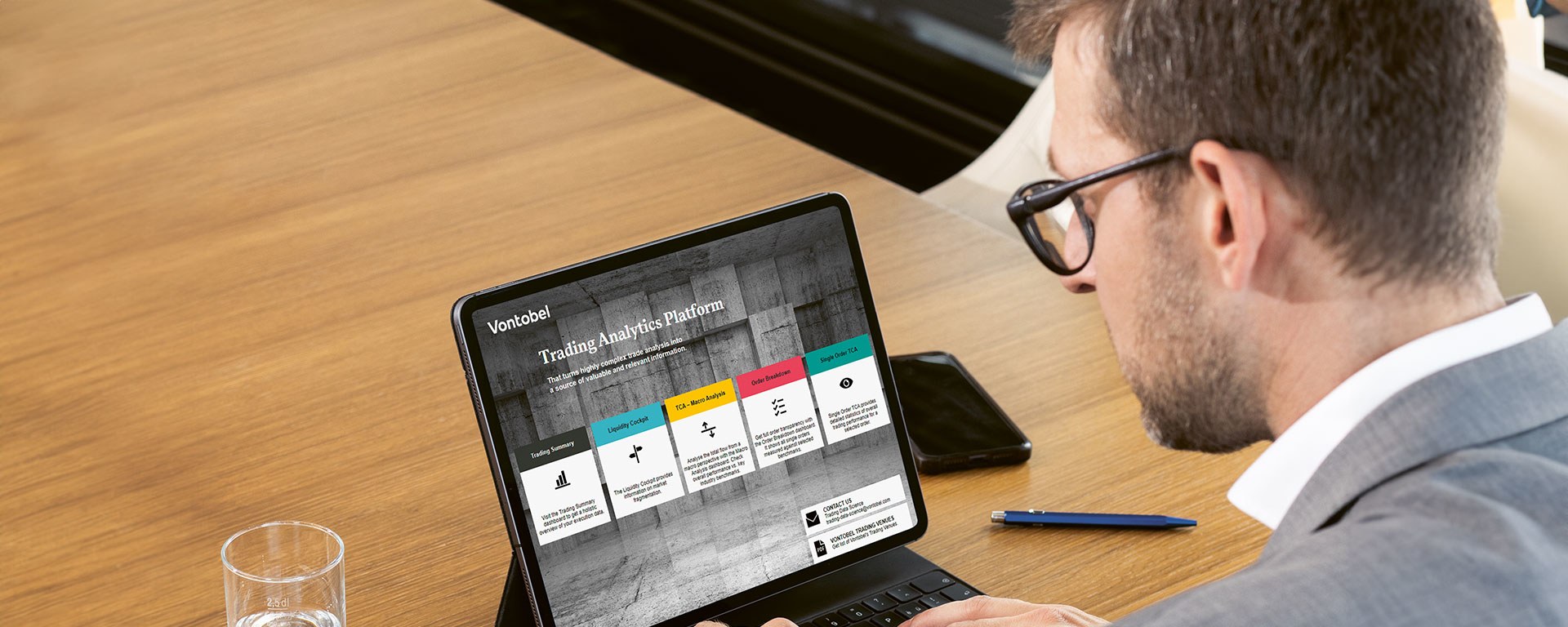 Ein Mann sitzt an seinem Tablet und schaut sich die Trading Analytics Plattform an.