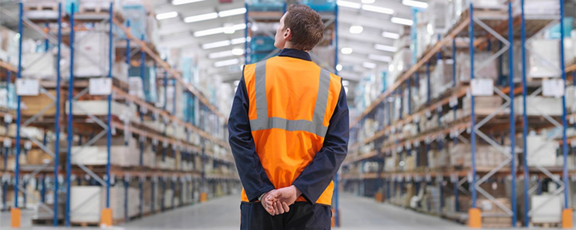 Man with orange vest standing in the warehouse