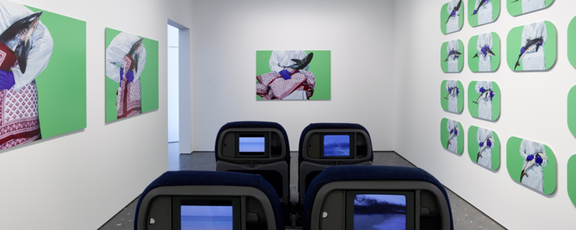 Ausstellung Zürich - Raum mit Kunstwerken an den Wänden und vier Kinosesseln in der Mitte.