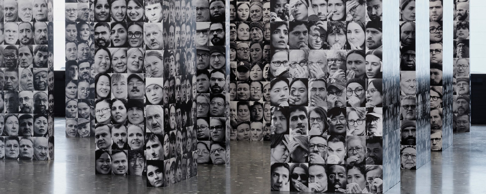 Foto der Kunstausstellung mit einem Kunstwerk von Augustin Lignier: Mehrere Gesichter sind auf Säulen abgebildet.