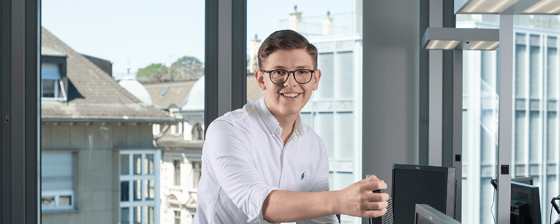 An IT apprentice at Bank Vontobel looks into the camera with a laugh.