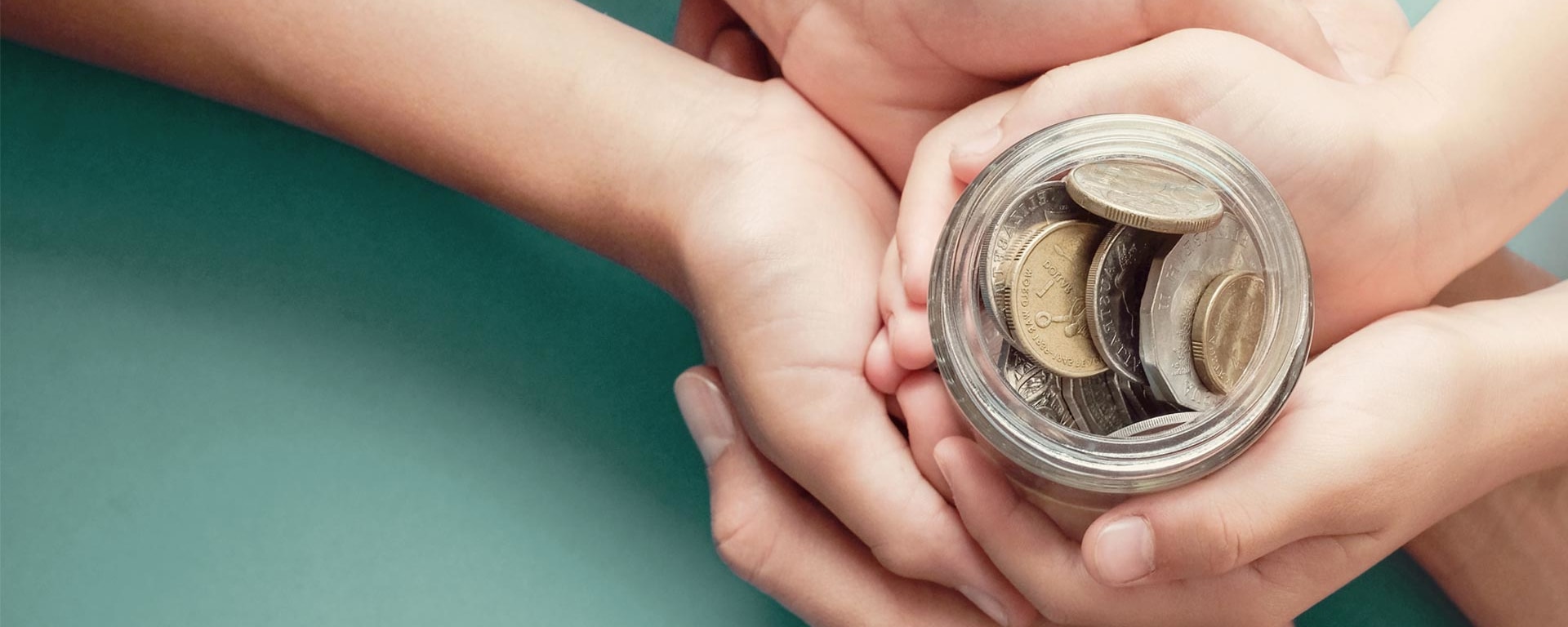 A pair of hands hold a glass filled with money