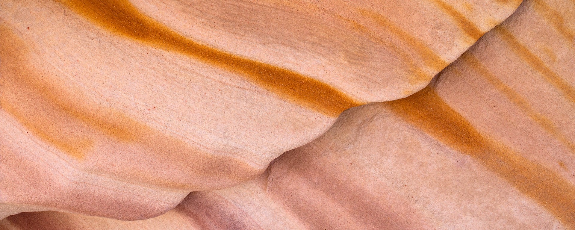 Abstract close-up of layered sandstone with flowing orange and beige patterns