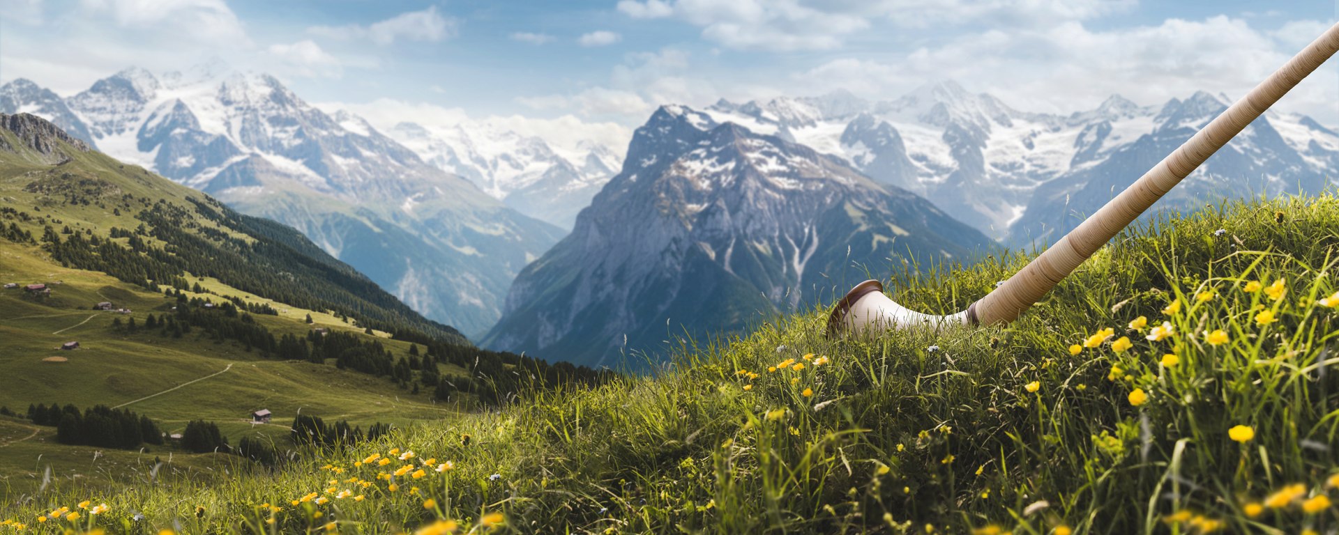 Photo of the Swiss mountain landscape and an alphorn standing in the grass