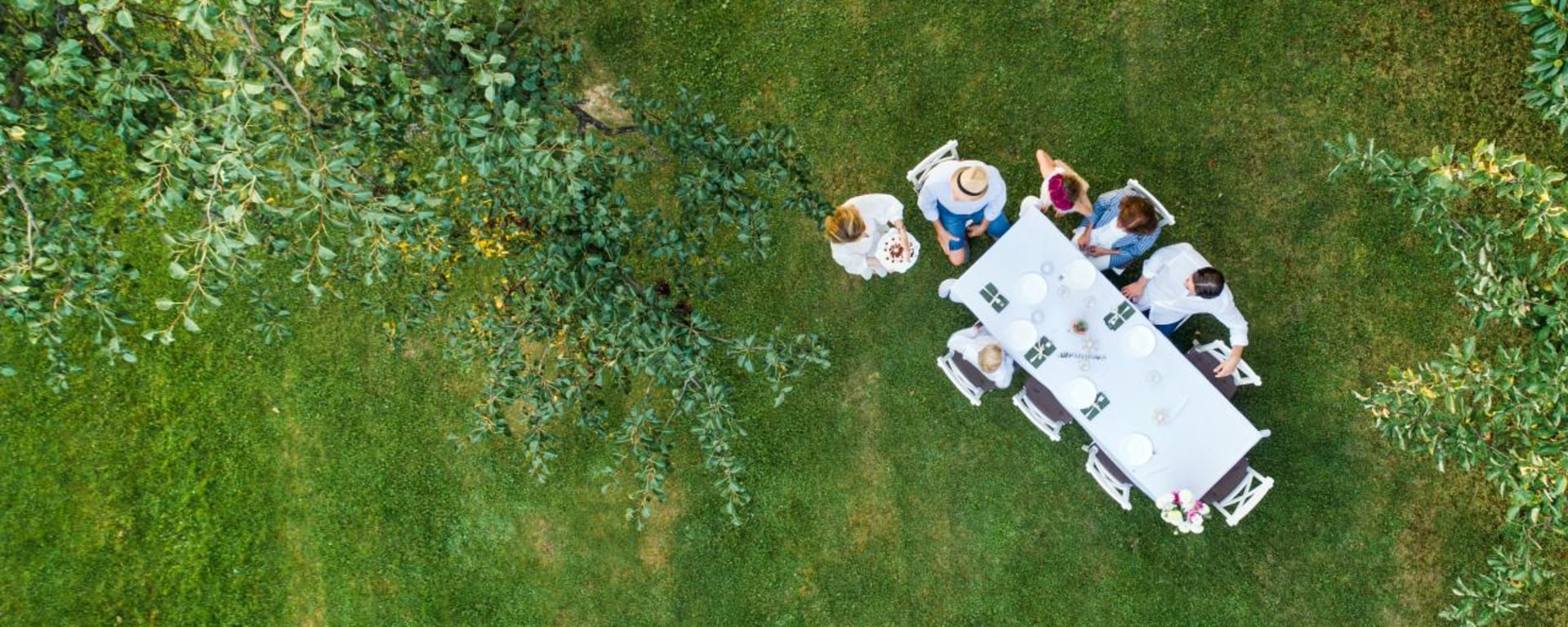 Multi-generational family gathered around a garden table, illustrating how estate planning begins by bringing everyone to the table to discuss the future estate distribution