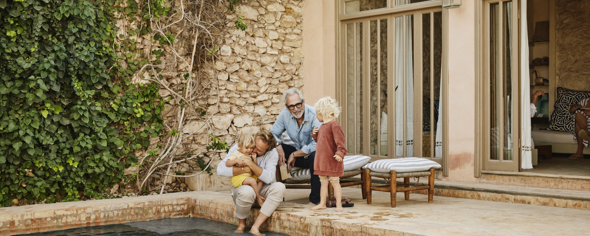 Grandparents, parents, and children gathered by a pool, illustrating that real estate division requires proactive estate planning