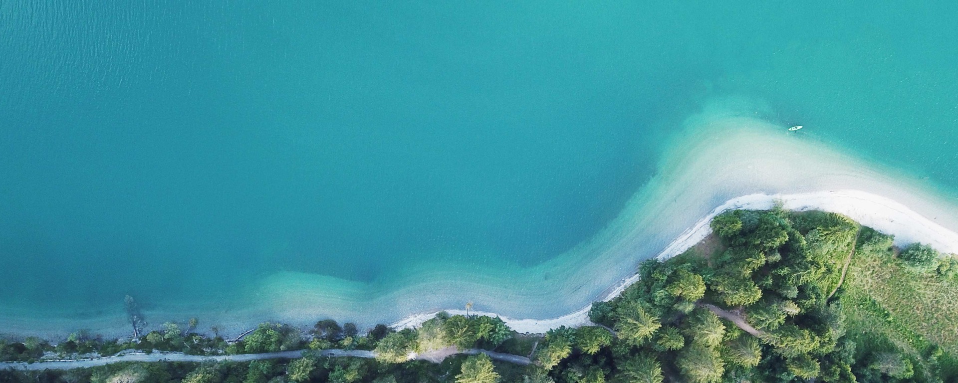 Bild eines Strandes aus der Vogelperspektive, auf dem man auch einen Kajakfahrer sehen kann.