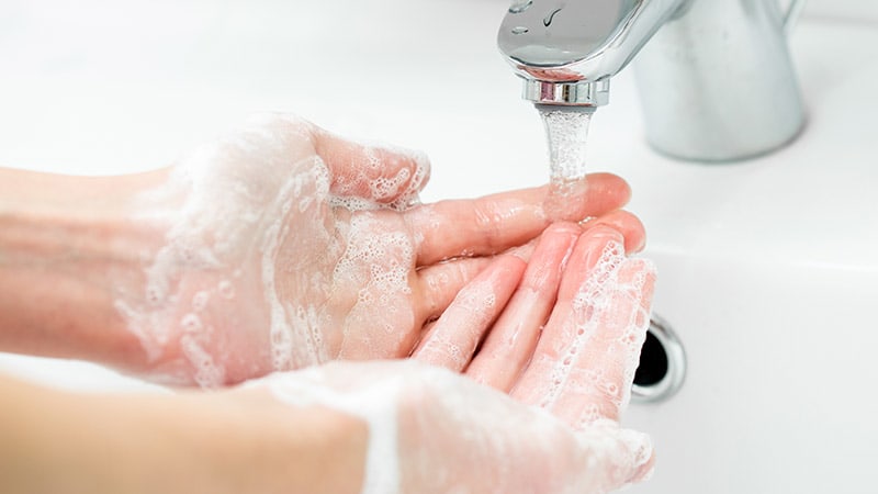 Eine Person wäscht sich die Hände mit einer Seife, die Corona visrus symbolisiert.
