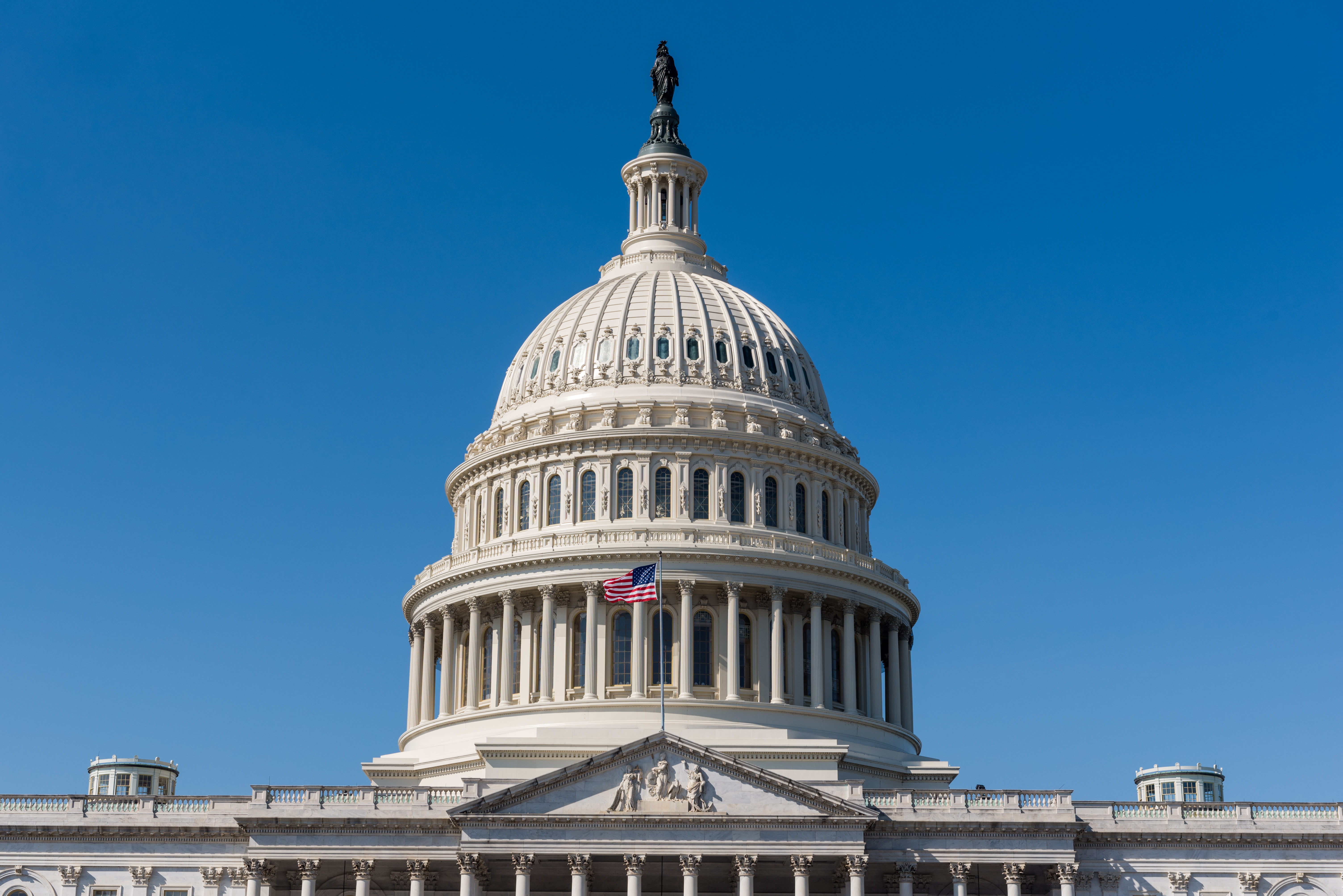 Photo of the dome of a white building with an American flag on top