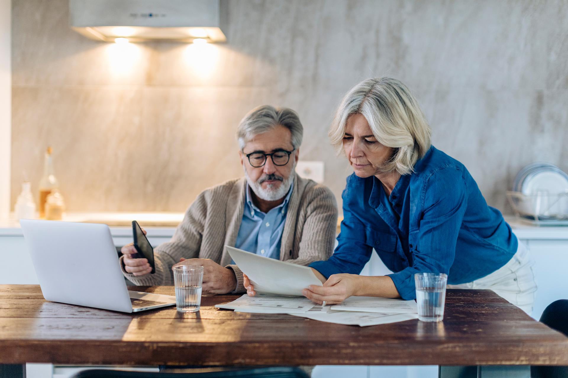 Un homme et une femme âgés sont assis ensemble à leur bureau et réfléchissent à leurs avoirs de libre passage et à la manière dont ils peuvent optimiser leurs rendements.