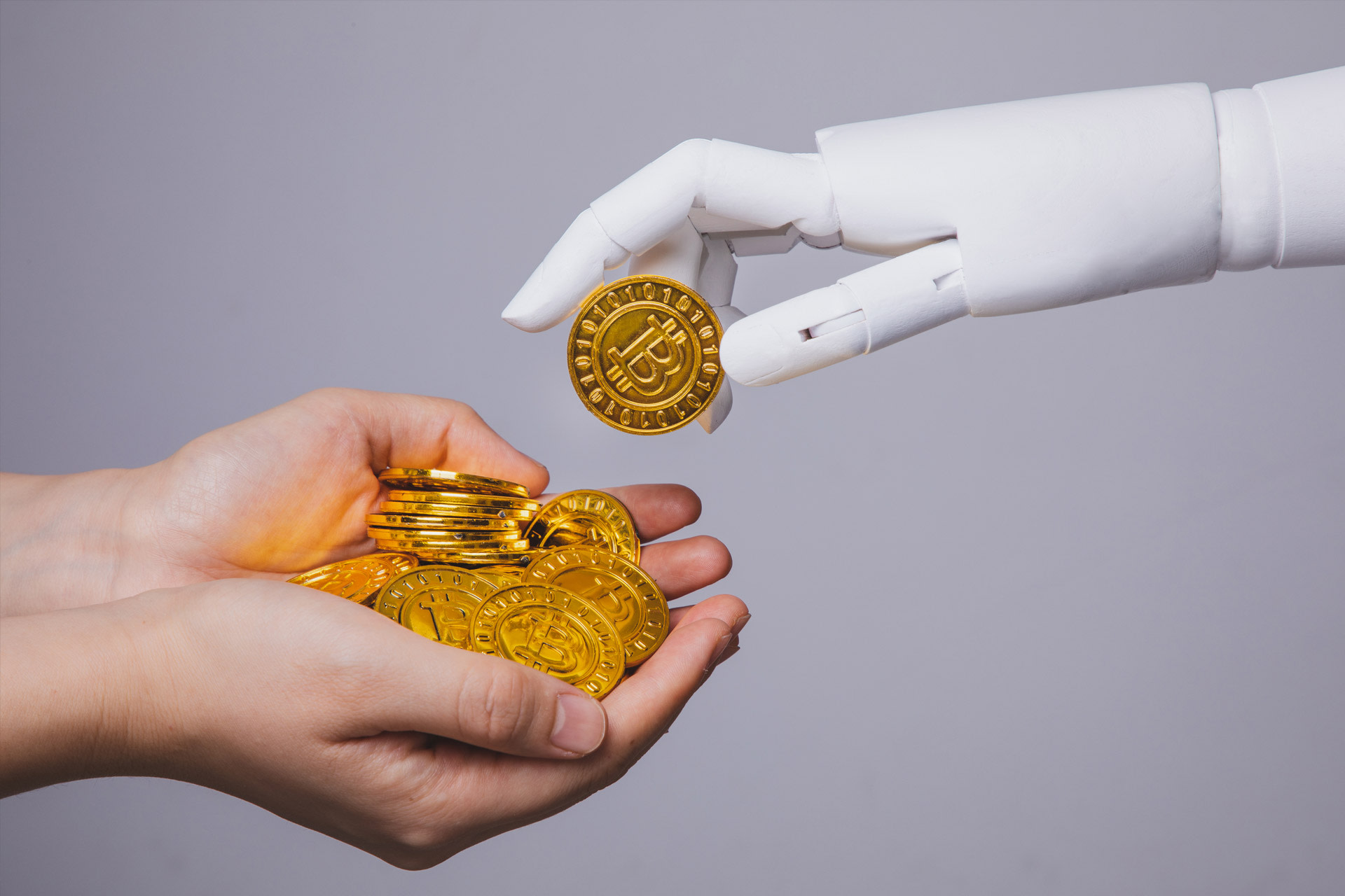 Una mano robotica pone bitcoin nelle mani di un essere umano.