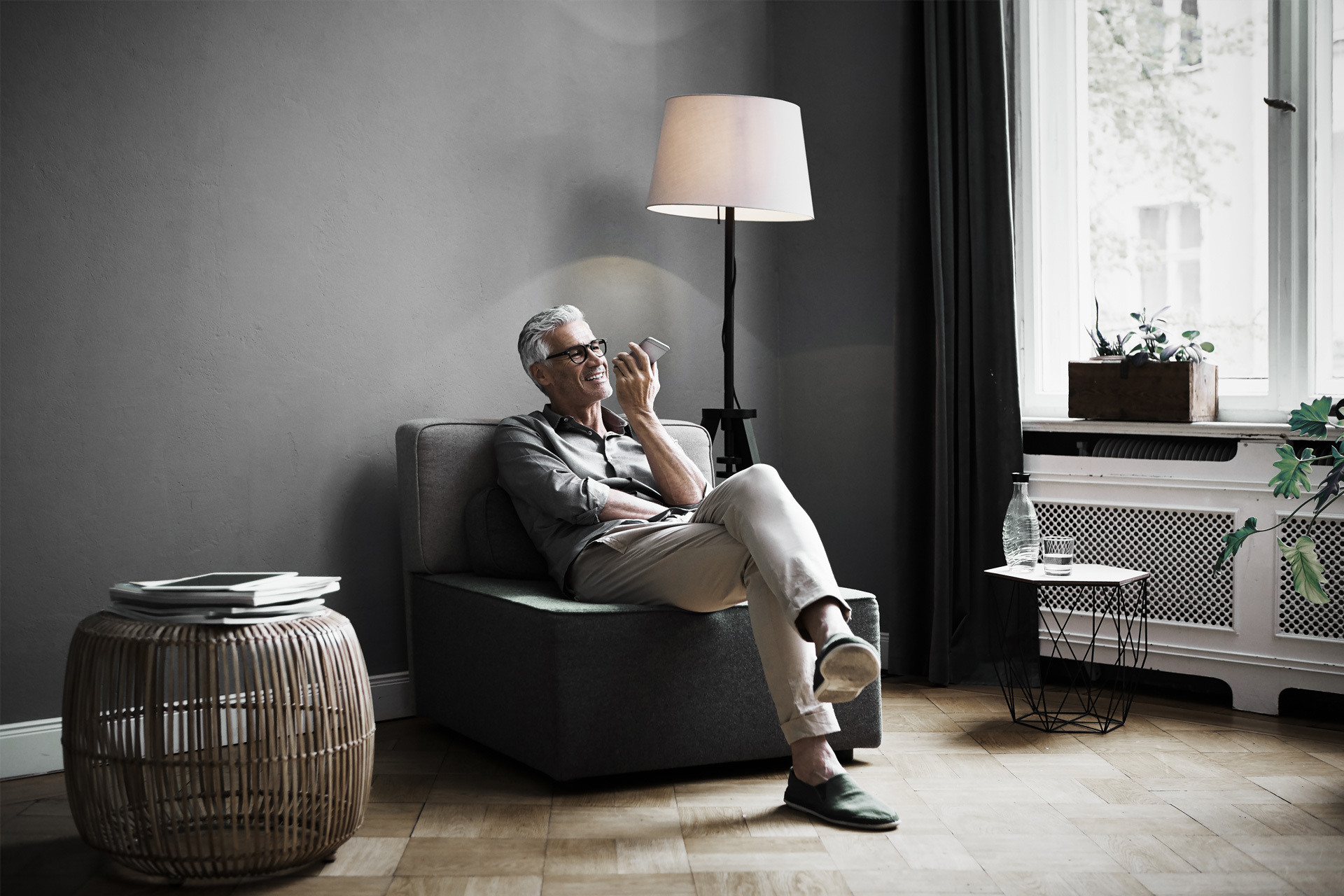 A man sits in his armchair with his smartphone in his hand while making investments.