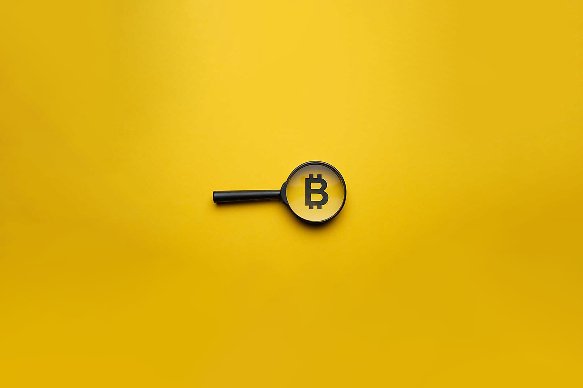 Eine Lupe mit einem Bitcoin Icon auf gelbem Hintergrund symbolisiert die wichtigen Punkte für ein Investment in Kryptowährungen.