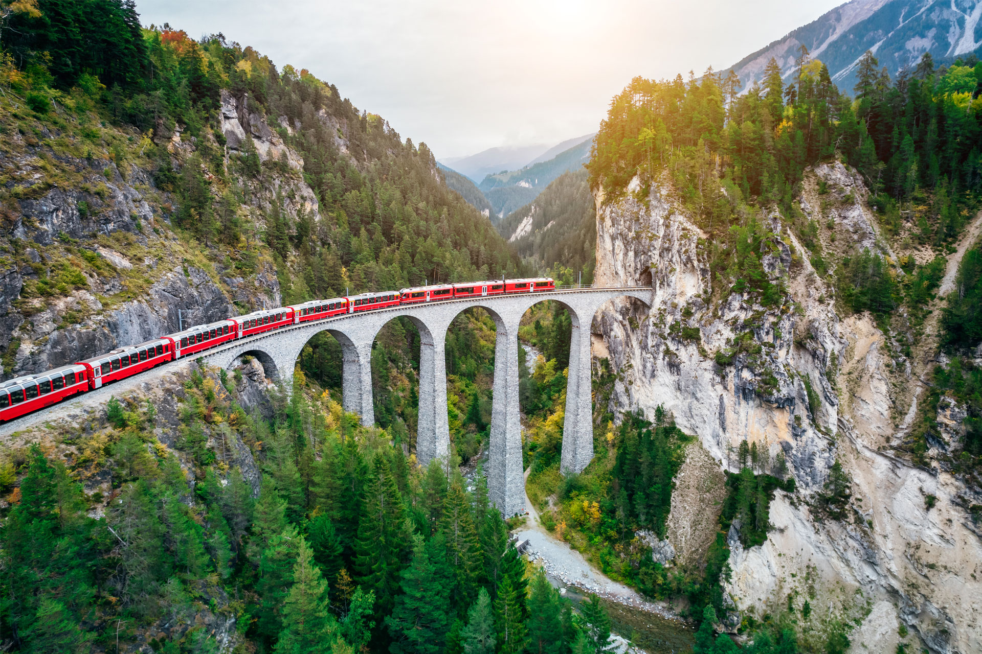 A red train crosses a viaduct. Symbolic image for a move to Switzerland.