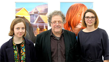 Three individuals posing in front of an art collection.
