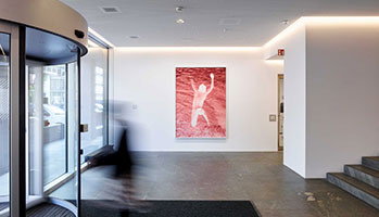 A person walking through a large building with a large painting in the background.