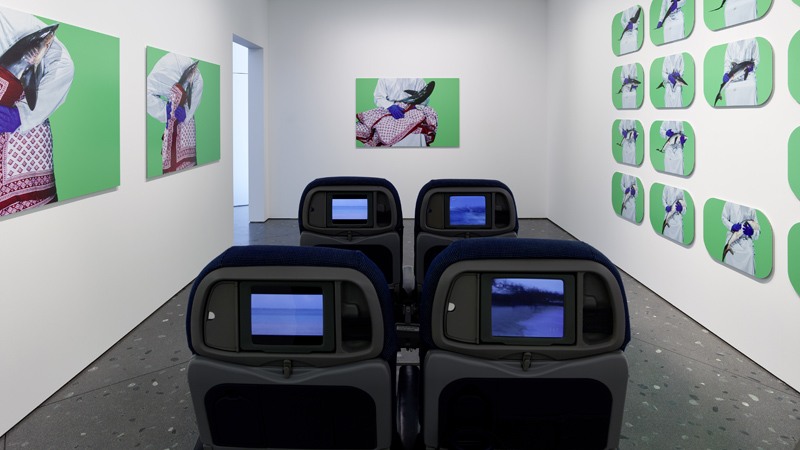 Exhibition Zurich - Room with artwork on the walls and four cinema chairs in the middle.