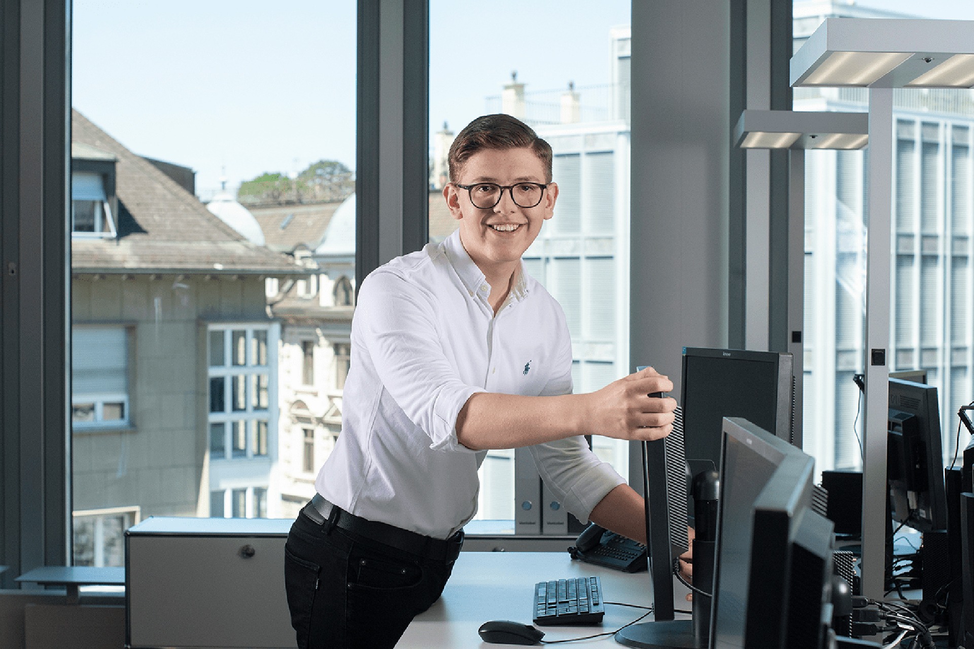 An IT apprentice at Bank Vontobel looks into the camera with a laugh.