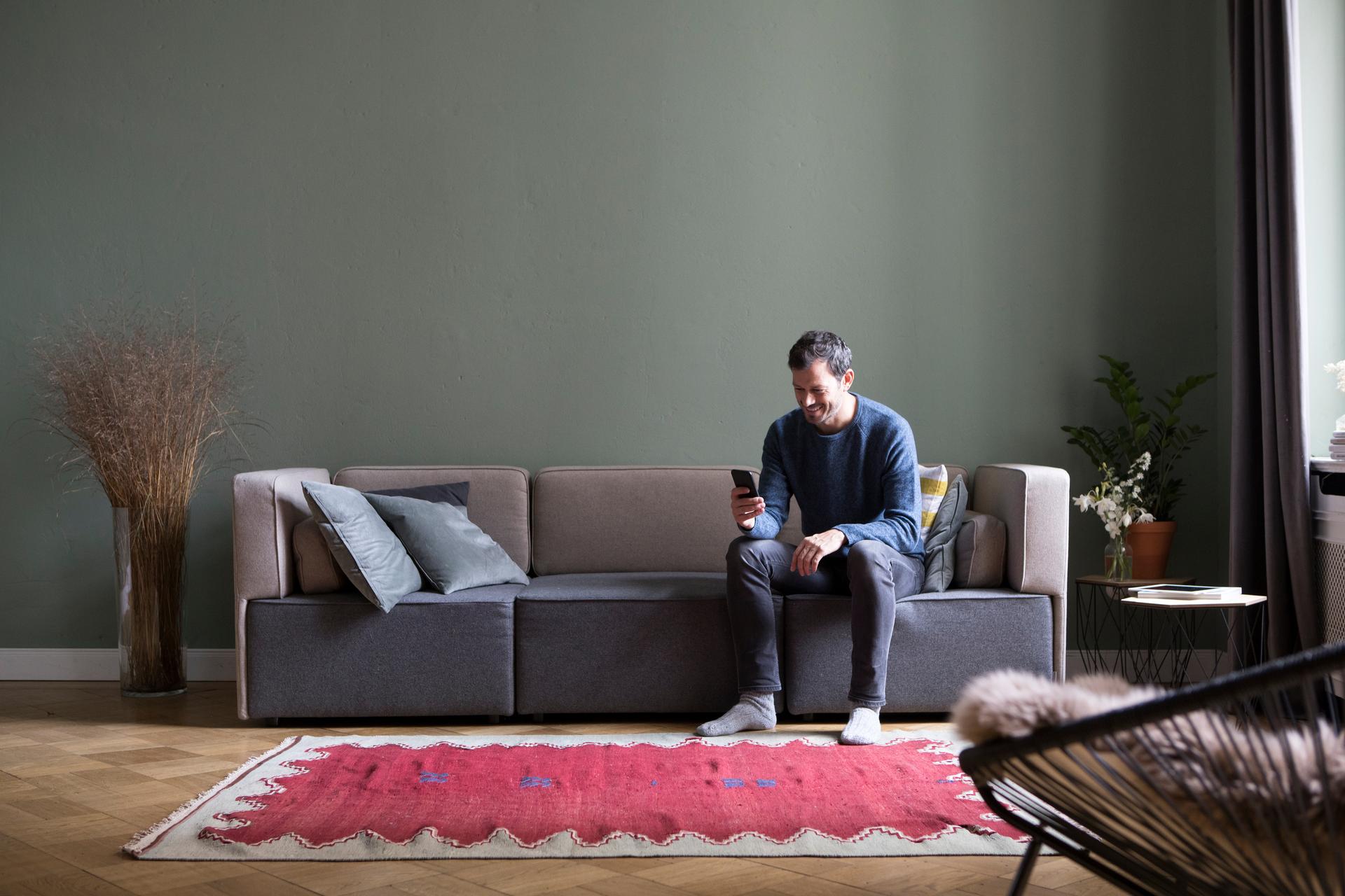 A man sitting on a couch, looking at his phone.