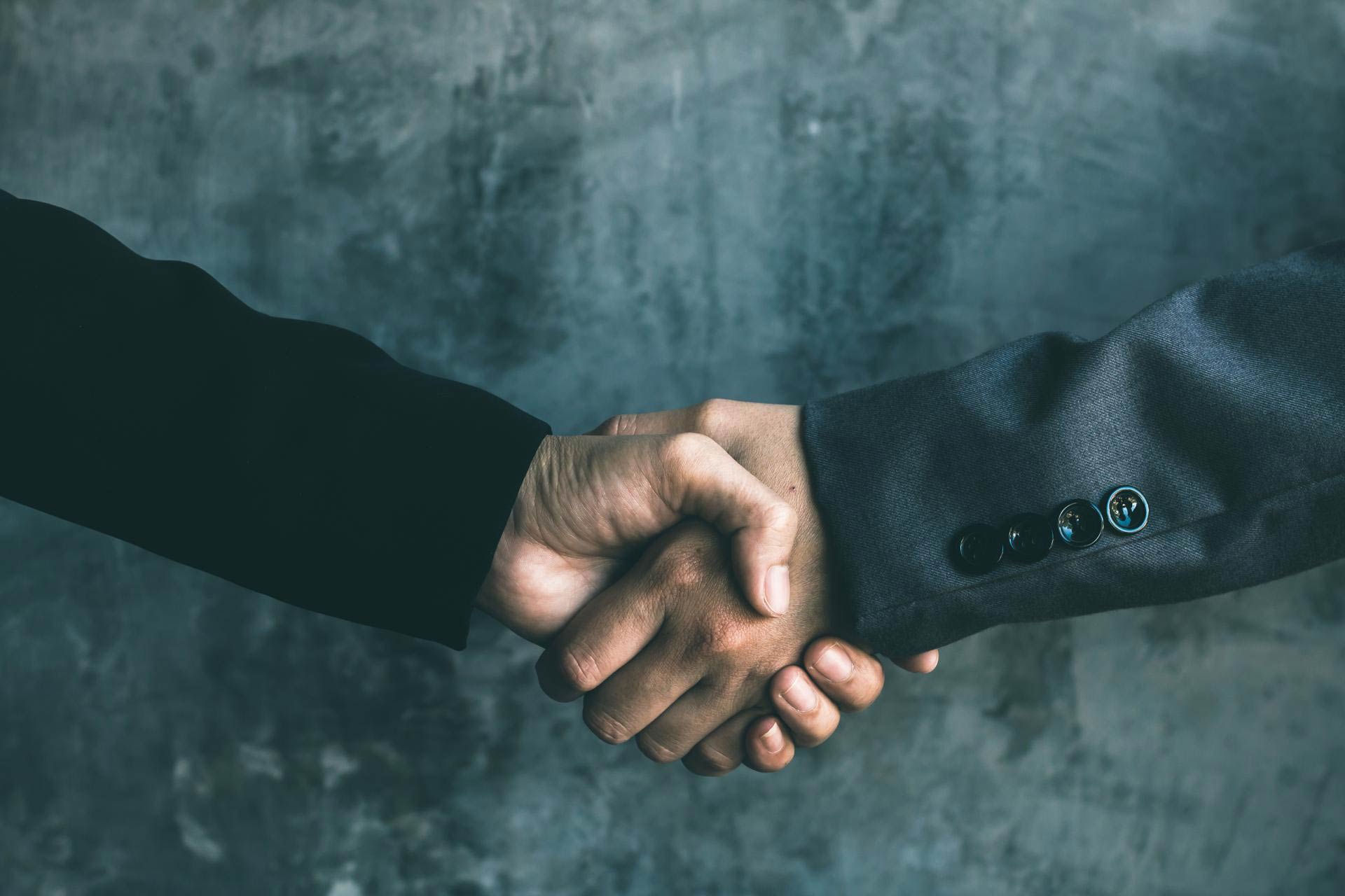 Two businessmen in suit shake hands in business relationship
