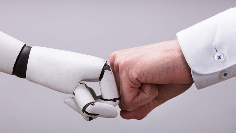 Un homme donne le poing à un robot et symbolisent les investissements thématiques de Vontobel, comme par exemple la technologie.