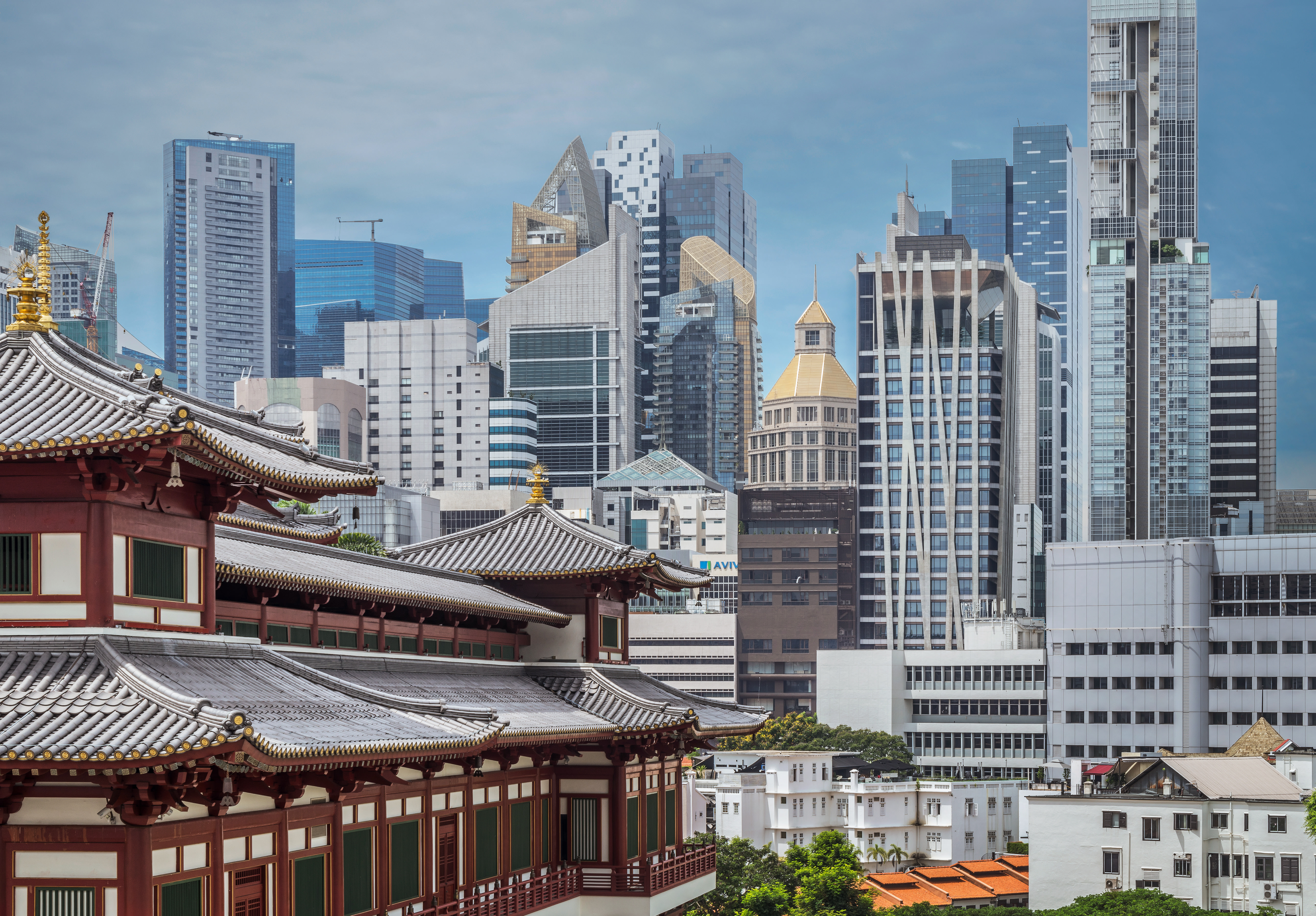 Ornate Asian-style temple with curved roof in foreground against a clear-sky skyline of modern glass-and-steel skyscrapers.
