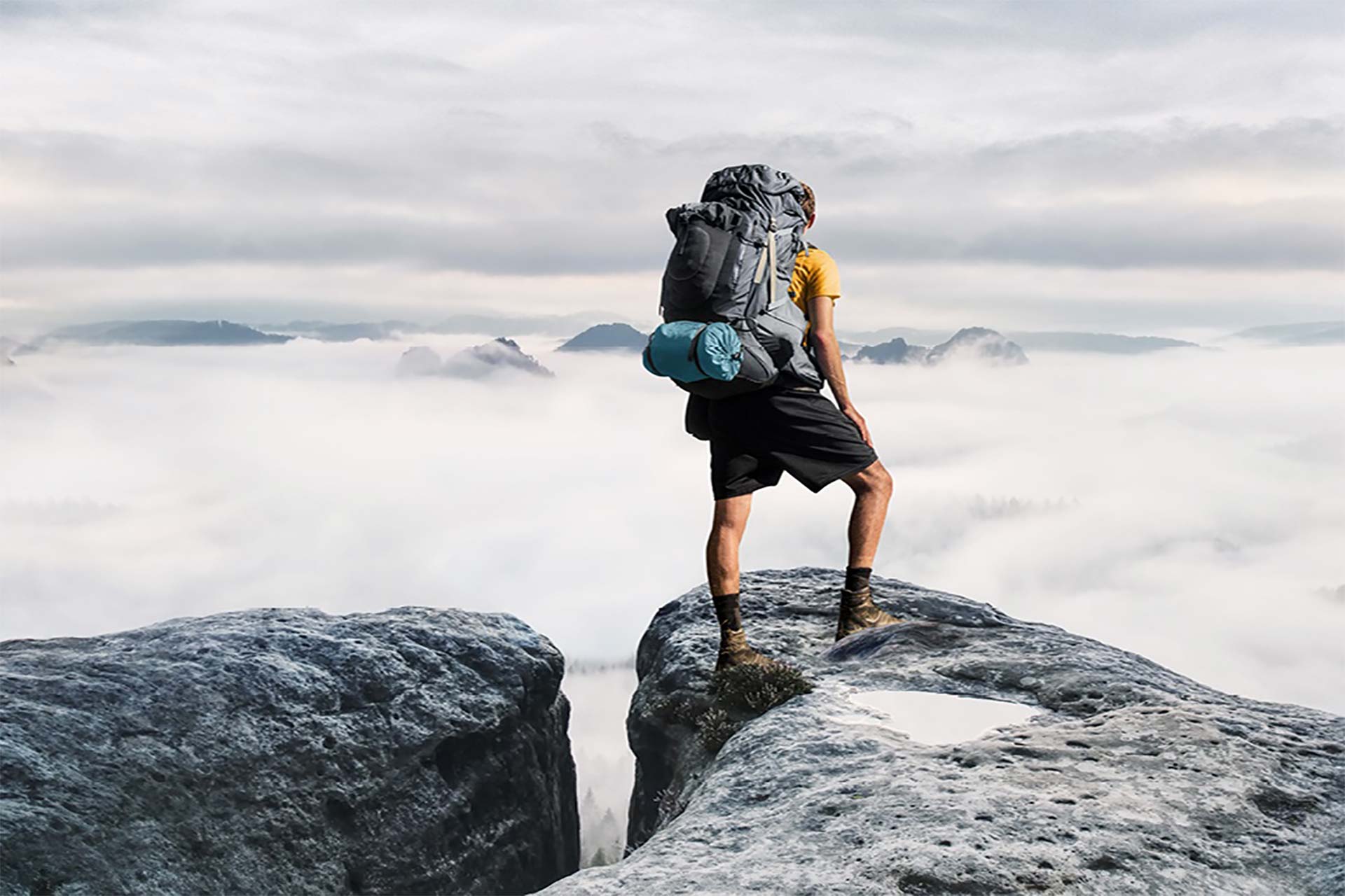 Investment Outlook 2023: A hiker stands on a cliff and looks at the panorama.
