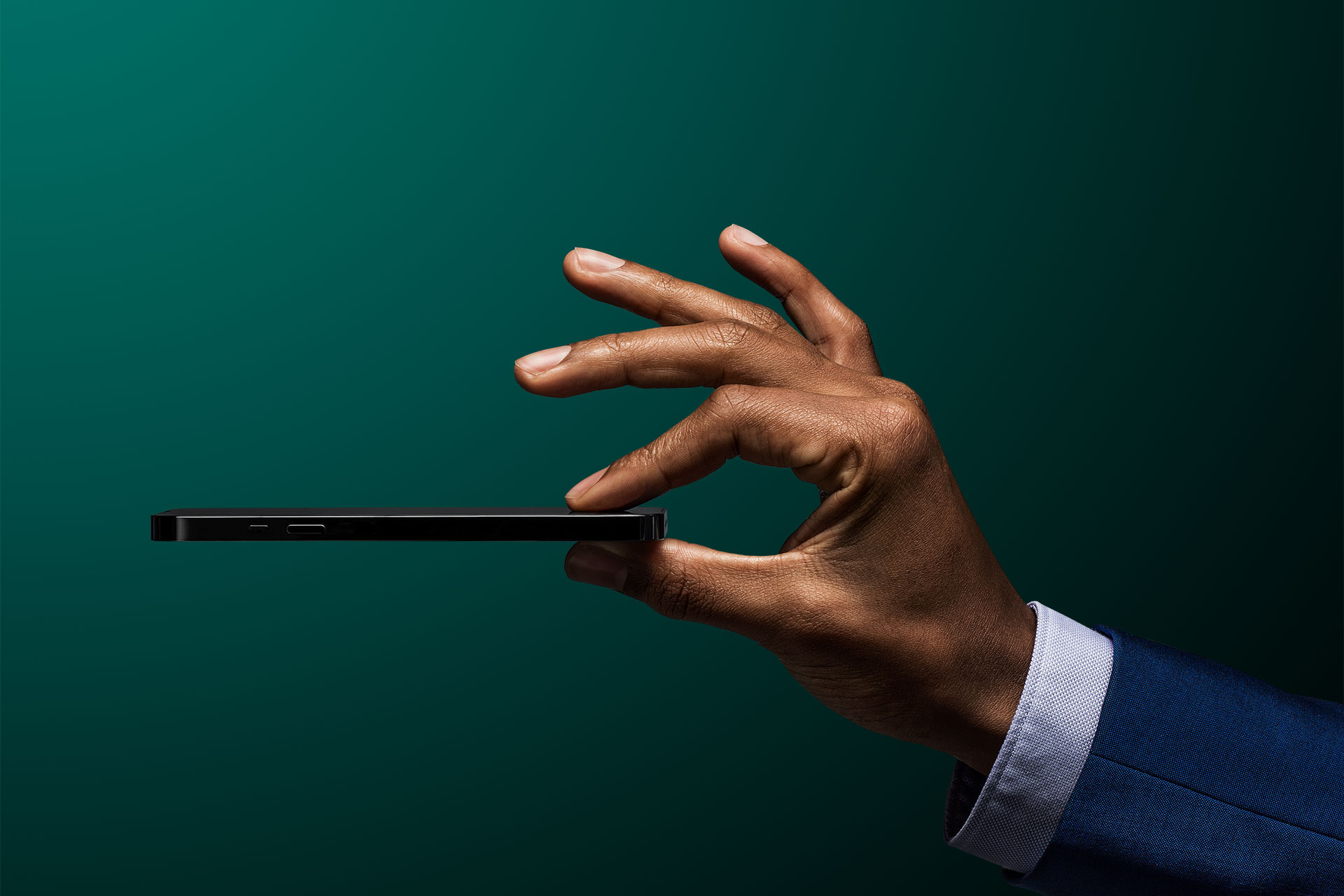 Un uomo d'affari tiene in aria il suo cellulare davanti a uno sfondo verde scuro, simbolo dell'app di investimento Vontobel Volt.
