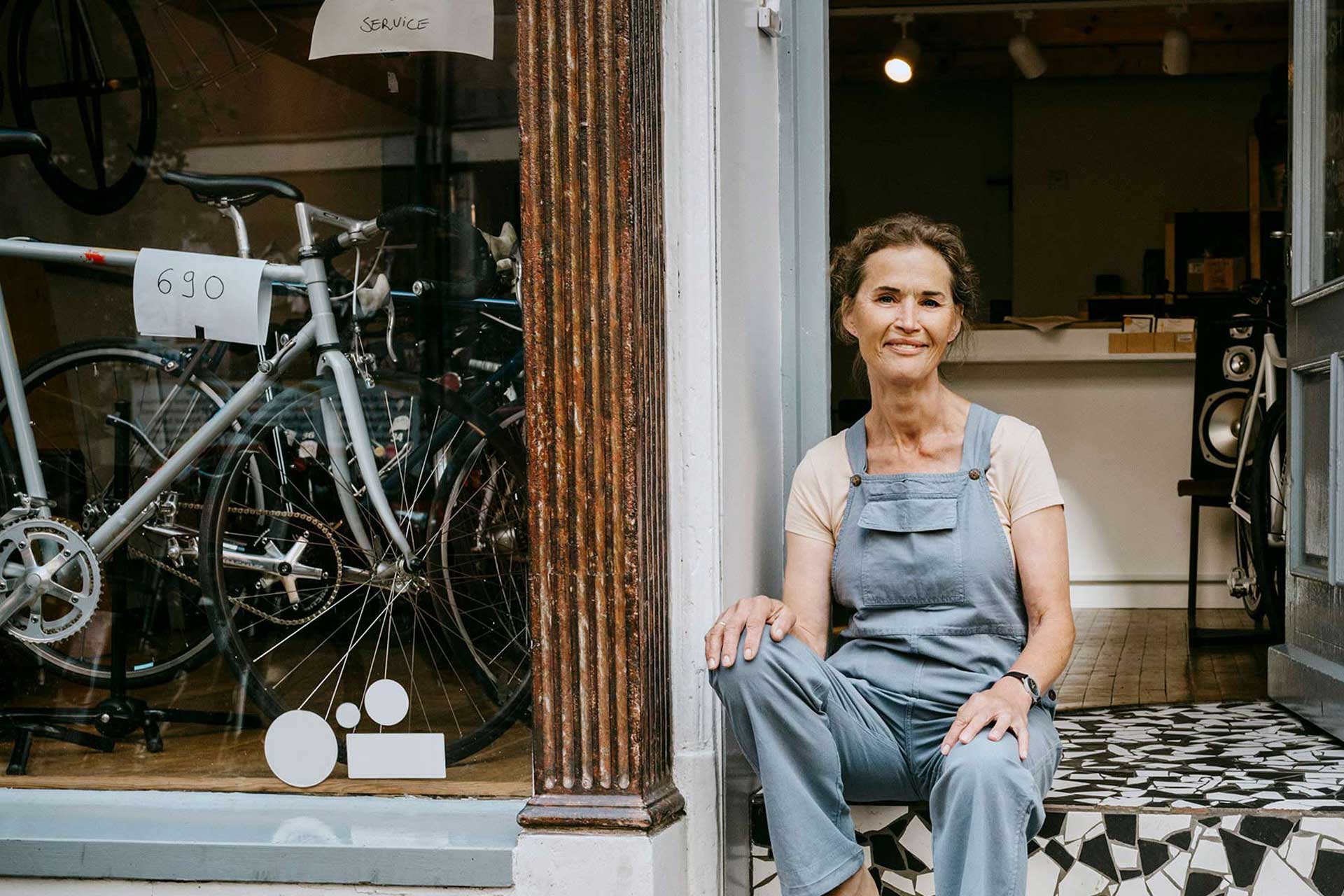 A woman sits on stairs in front of her own bike store