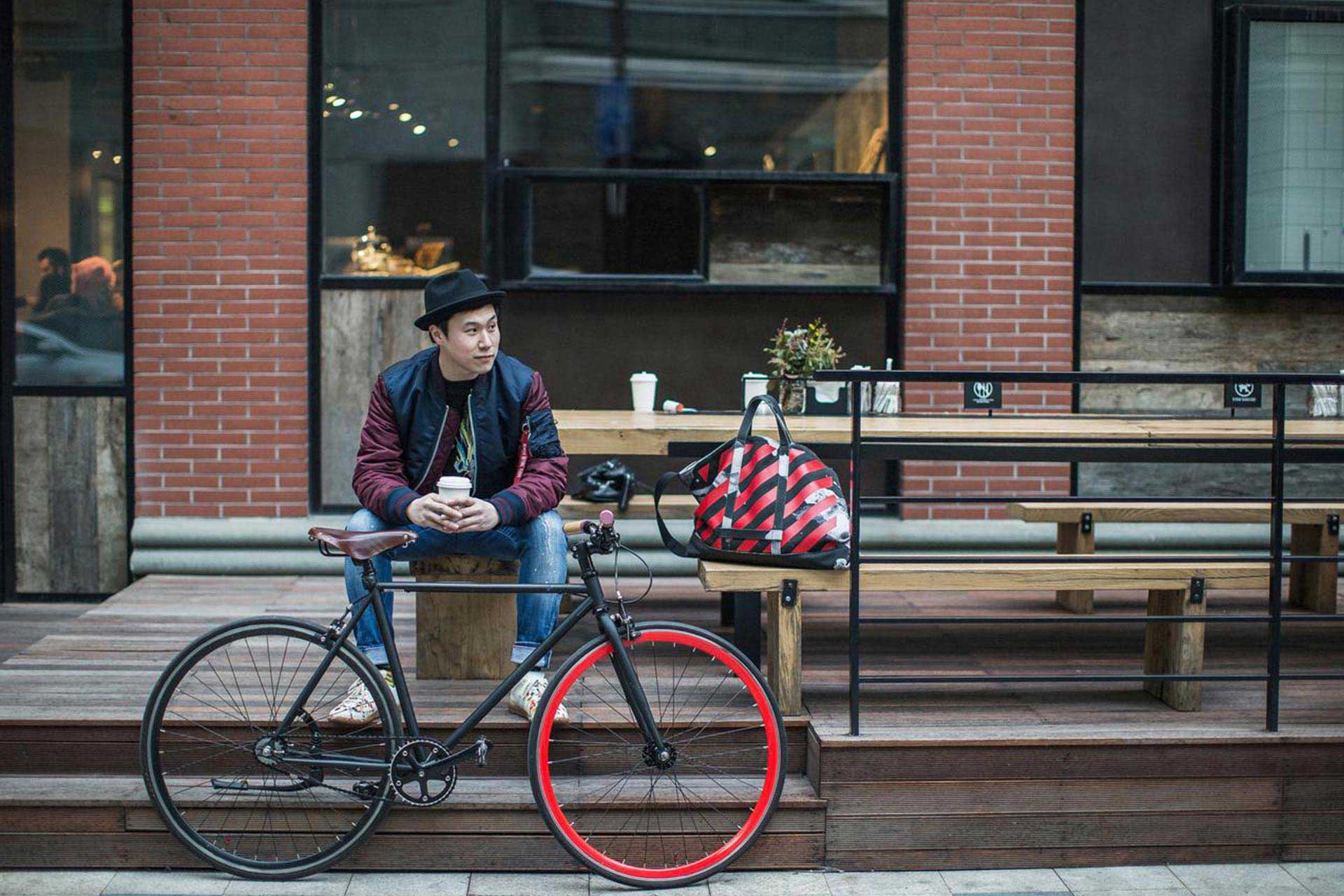 Un jeune homme assis sur les marches à côté de son vélo