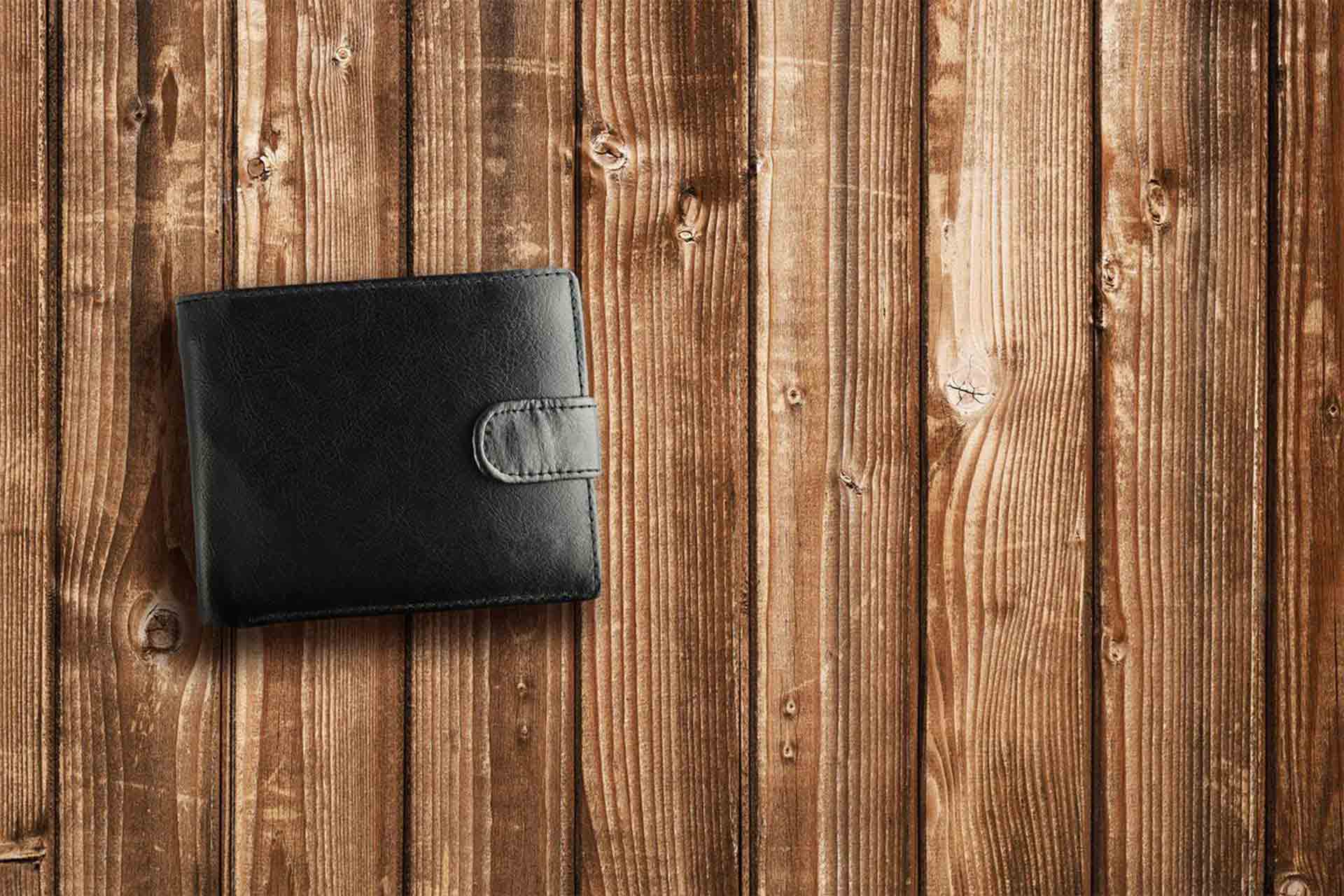 A leather wallet lies on a wooden table