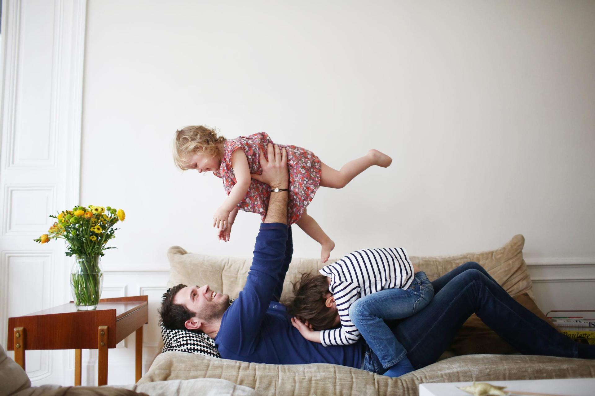 Married father playing with his children on a sofa, illustrating that estate division between a surviving spouse and joint children can be adjusted through proactive estate planning