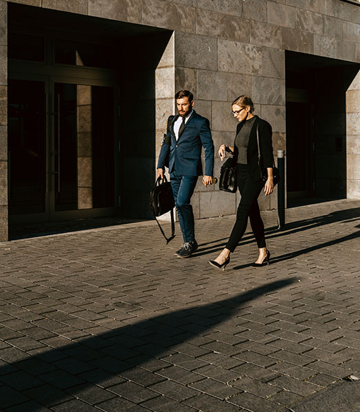 A business woman and a business man walking across a square together