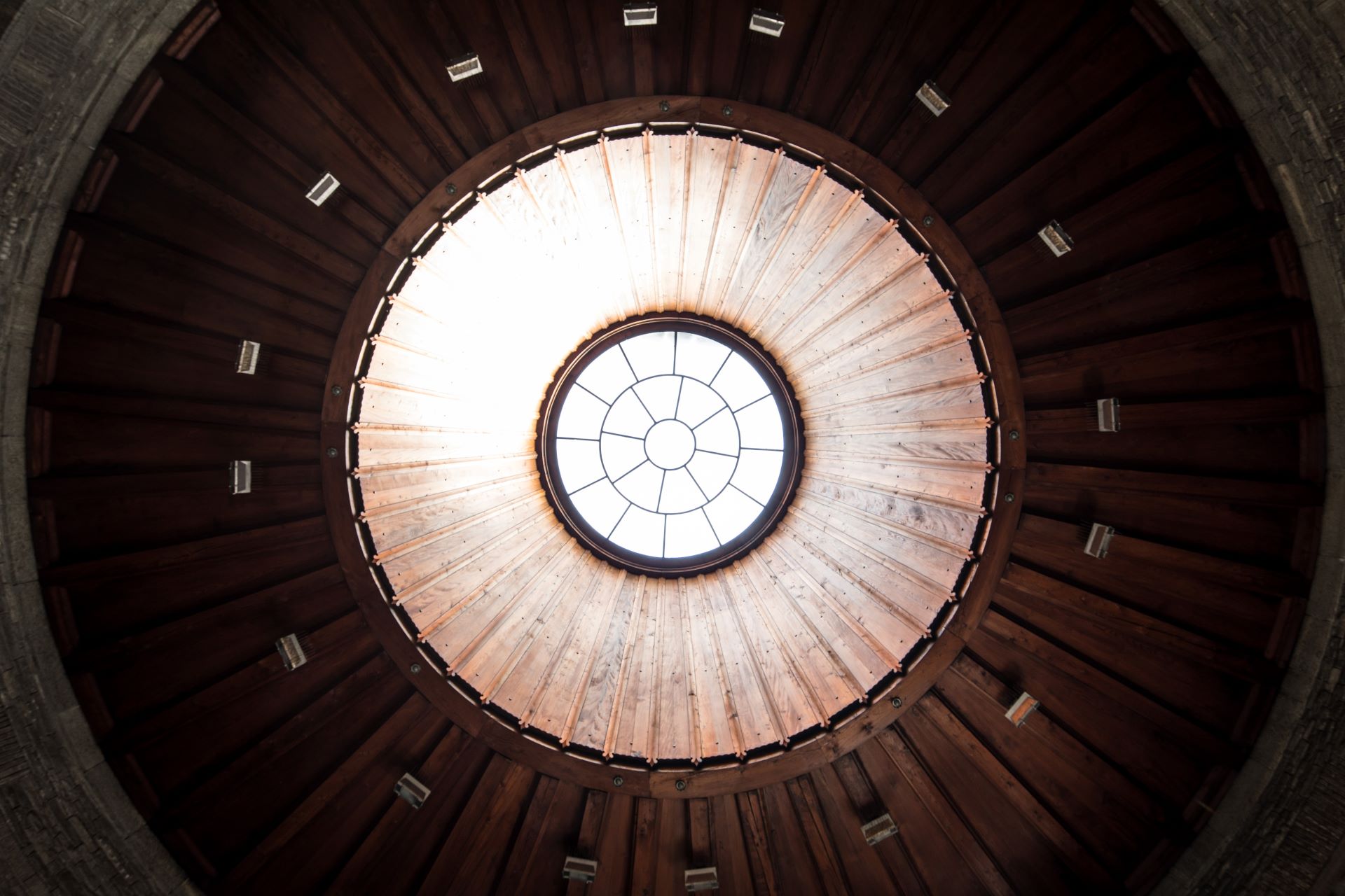 Primo piano architettonico di un lucernario circolare in mezzo a un soffitto a cupola in legno con design geometrico