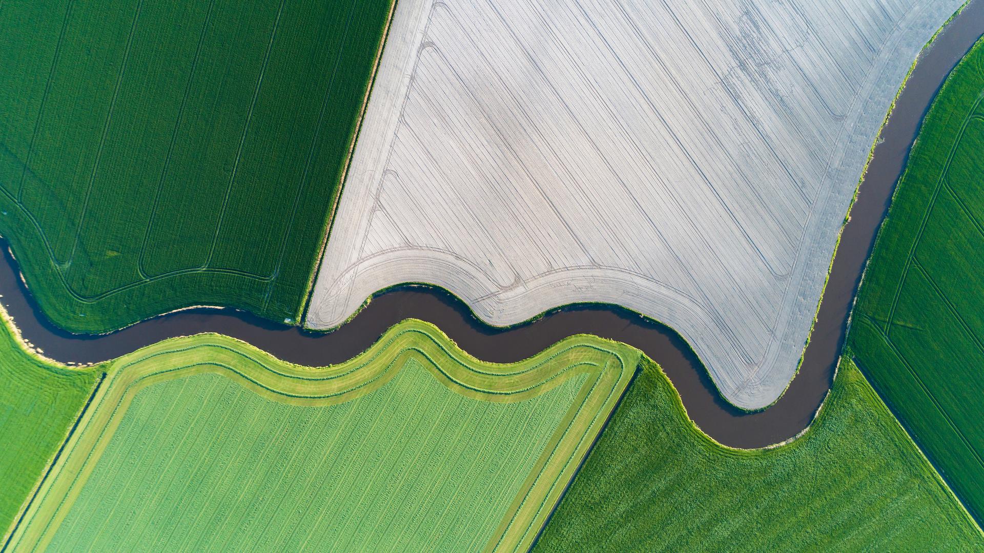 Top down view on a river winding through agricultural fields