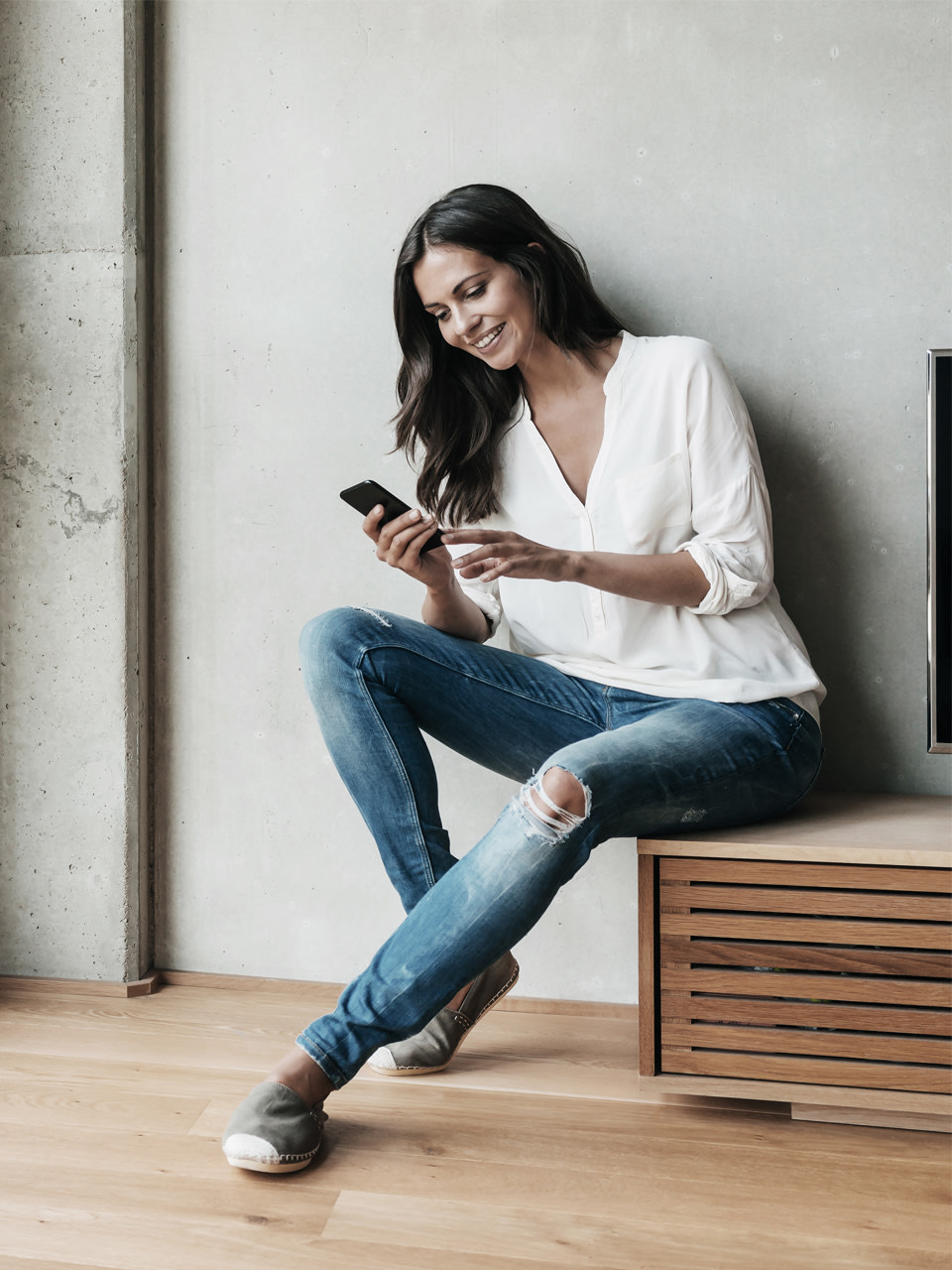 A woman sits on her TV furniture and watches the volt by Vontobel newsletter.