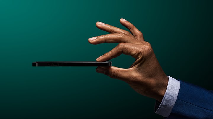 Eine Hand hält ein Smartphone zwischen ihren Fingern. Symbolisches Bild für die Investitionskompetenz, die in der Volt-App steckt.